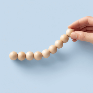 Hand placing wooden bead on line