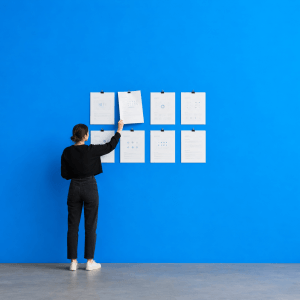 Printable Habit Tracker (Free PDF): One Month, One Page - person unclipping one worksheet from a wall of eight pinned printouts