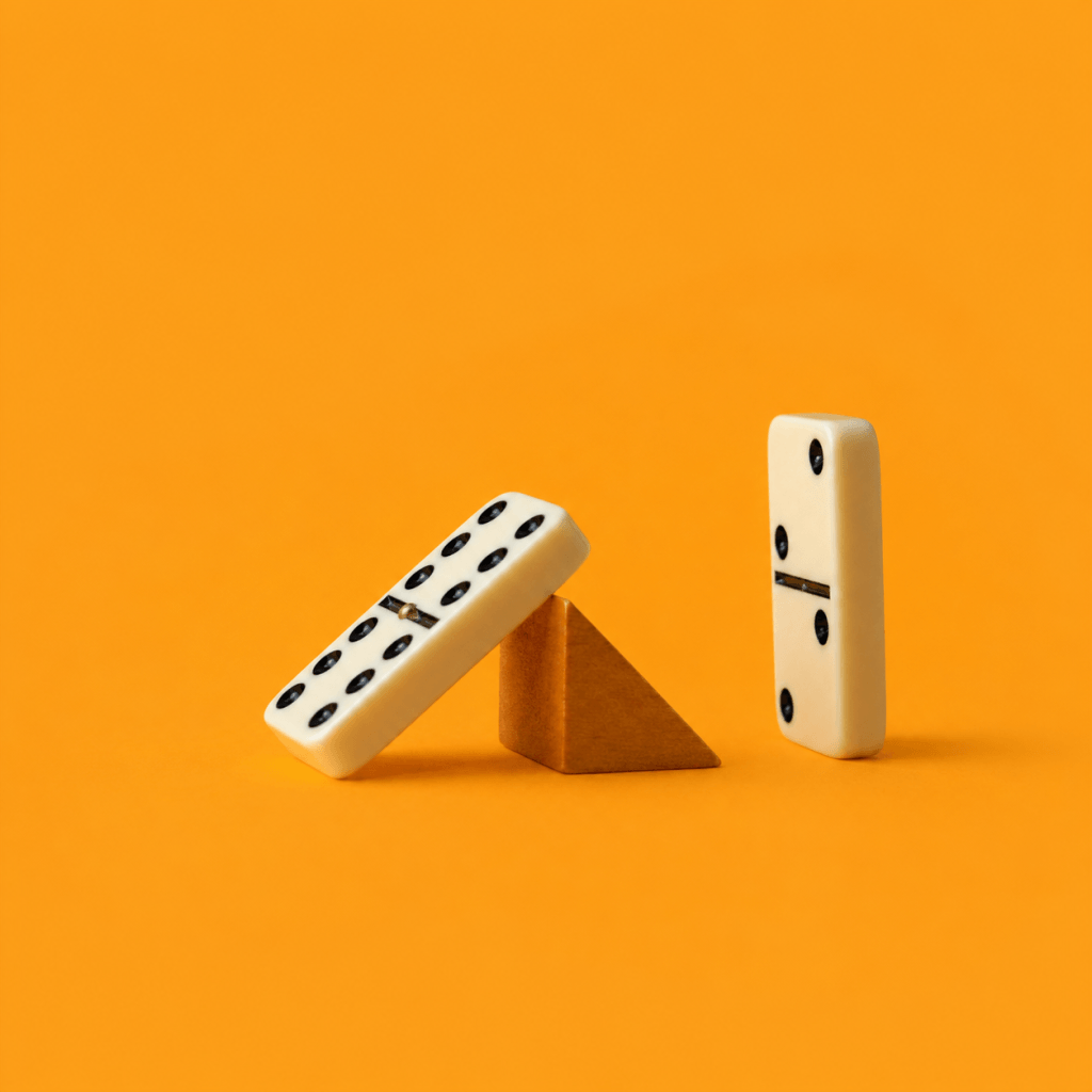 The Two-day Rule: Recover From a Missed Habit (2026) - single domino caught mid-fall, stopped by a small wedge before the next one