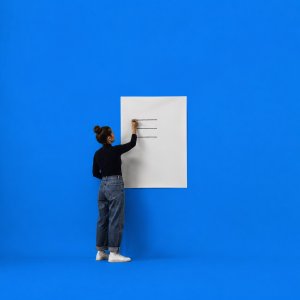 Read your Insights and Wall of Wins in the Life Goals App: a person writing three short lines on a large blank poster with a marker