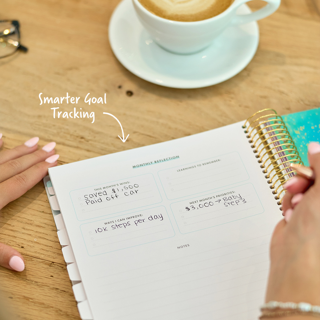 Best Goal Planners for 2027: Paper, Tablet and App 4 Hand writing on the Monthly Reflection page of the Ramsey Goal Planner under the callout Smarter Goal Tracking